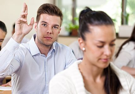 Student male raising his hand in university class
